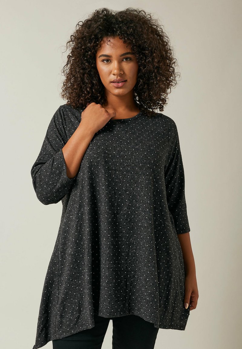 Schwarzes Tunika-Oberteil mit dreiviertellangen Ärmeln, das aus einem strukturierten Gewebe mit kleinen silbernen Punkten besteht, runder Ausschnitt und einer lockeren Silhouette.