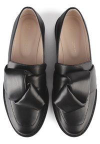 Schwarze Lederloafers mit einer großen Stoffschleife auf der Zehenpartie, glatte Oberfläche, runde Zehenform und minimalen Nähdetails.