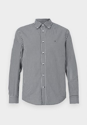 Černo-bílá kostkovaná košile s dlouhým rukávem, s button-up přední částí a sklopeným límcem. Vyznačuje se slim fit střihem a malým logem na hrudi.