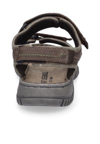 Ruskeat sandaalit, joissa on useita säädettäviä hihnoja, pehmustettu pohja ja teksturoitu kumipohja. Ominaisuuksiin kuuluu avonainen kantapää, joka lisää hengittävyyttä.