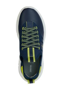 Zapatilla de deporte azul marino con parte superior de malla texturizada, acentos en amarillo-verde, cordones redondos y suela blanca. Presenta un logo en la plantilla y en la lengüeta trasera.