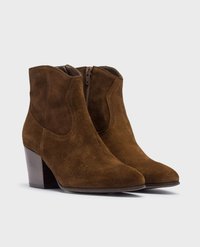 Botines de ante marrón con punta afilada y un tacón de madera de 7 cm. Cuentan con una cremallera lateral para una fácil colocación y tienen una textura suave.