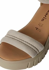 Sandalo platform in suede beige con una ampia fascia caratterizzata da doppie cuciture e una suola in gomma texturizzata. La fodera interna è in morbida pelle marrone chiaro.