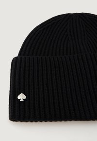 Berretto in maglia nera con texture a costine, caratterizzato da un piccolo emblema a forma di picche in argento sul lato. Design morbido e casual, adatto per il clima freddo.