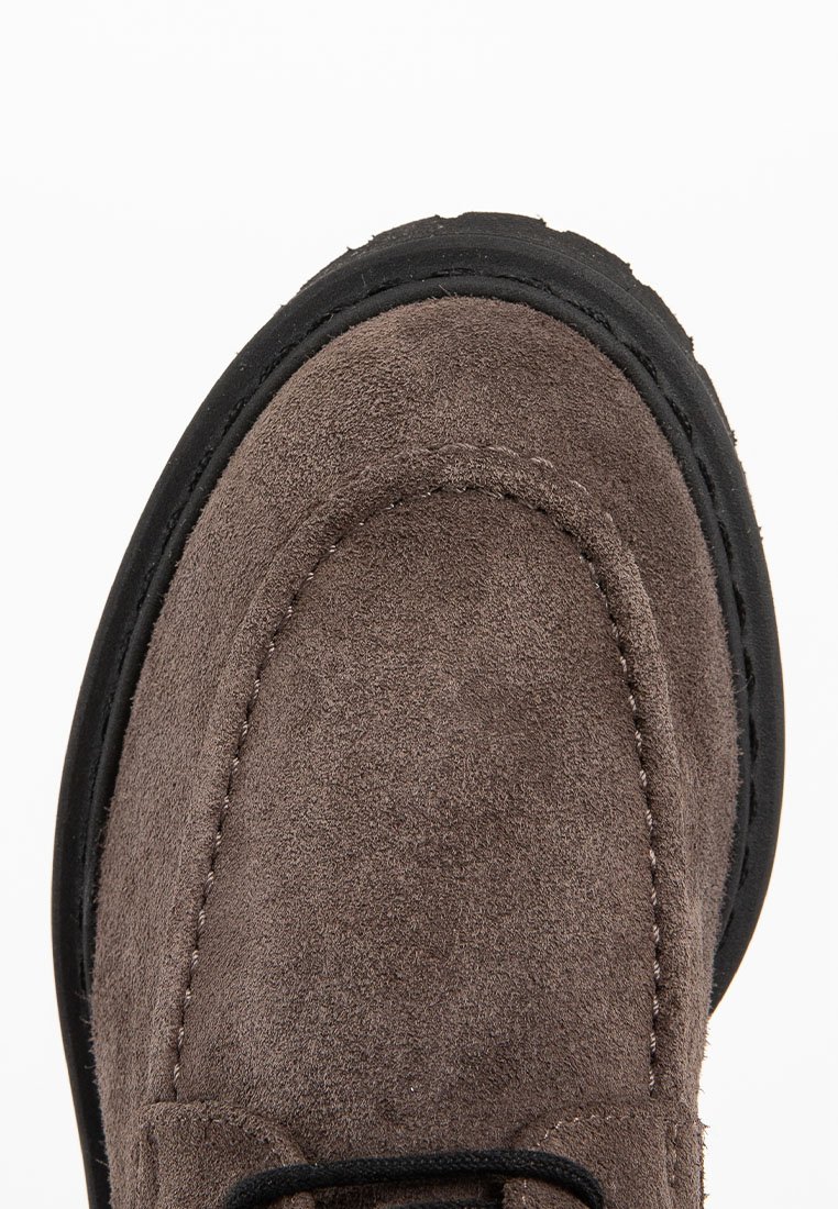 Brauner Wildlederschuh mit sichtbaren Nähten an der Zehenpartie und schwarzem Gummisohleneinsatz.