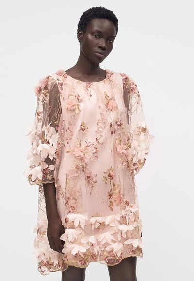 Μοντέλο που φοράει διάφανο ροζ φόρεμα με πολυεπίπεδες 3D floral εφαρμογές και κέντημα, με φουσκωτά μανίκια τριών τετάρτων και στρογγυλή λαιμόκοψη.