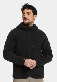 Svart fleecejacka med hög krage, blixtlås fram, textilerad yta och åtsittande manschetter. Har en horisontell söm och diskret logotyp.