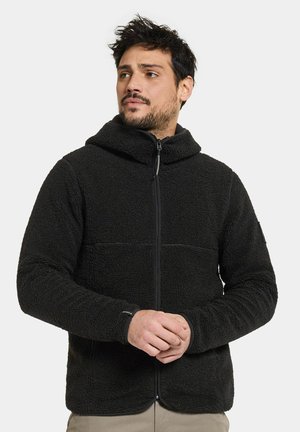 Veste en polaire noire avec un col haut, fermeture éclair à l'avant, tissu texturé et poignets ajustés. Présente une couture horizontale et un logo discret.