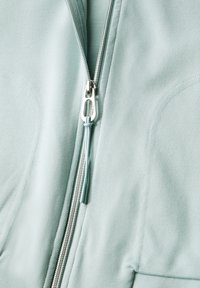 Jasnoniebieska tkanina z srebrnym zamkiem błyskawicznym, z uchwytem w postaci odpowiadającego jasnoniebieskiego sznurka zawiązanego na supeł.