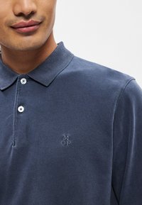 Ναυτικό μπλε πόλο μπλούζα φτιαγμένη από �βαμβάκι, με υφασμάτινη υφή, γιακά με κουμπί και κεντημένο λογότυπο "MOP" στο αριστερό στήθος.