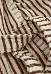 Close-up van beige en bruin gestreept badstof met gevouwen randen die de textuur en het patroon benadrukken.