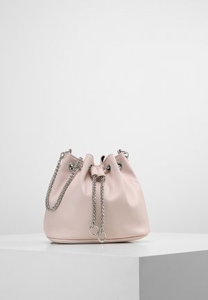 Lyserød læder bucket-taske med sølvkæde til lukning med snor og skulderrem på hvidt udstillingsunderlag.