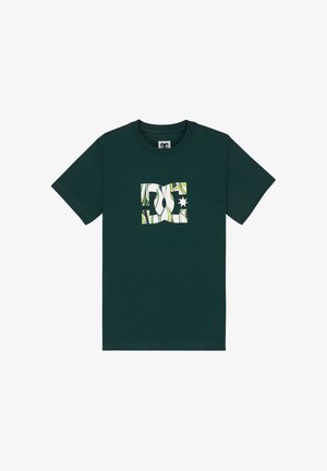 Ciemnozielona koszulka wykonana z bawełny, z białym logo oraz zielono-białymi abstrakcyjnymi wzorami i gwiazdą w centrum.