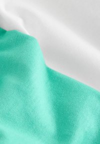 Tiffany és fehér pamut anyag, sima textúrával, látható kötött mintával, puha redőzéssel és átfedéses megjelenéssel.