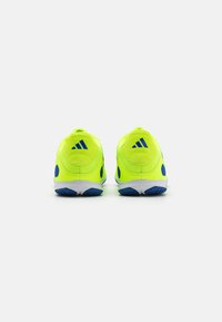 Zapatillas deportivas de color amarillo neón con detalles en azul, que presentan un upper texturizado y una suela blanca con elementos de tracción de caucho azul.