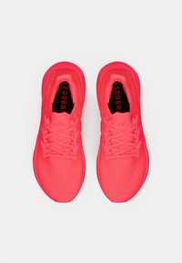 Chaussures de course rose vif avec une tige en mesh texturé, un col rembourré et un design à lacets. Comprend un marquage "boost" noir sur la semelle intérieure.