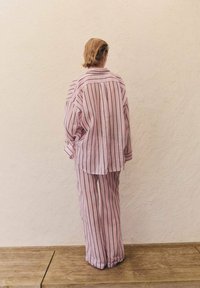En överdimensionerad skjorta med rosa och vita ränder samt matchande byxor i lätt tyg, med en avslappnad passform och långa ärmar.
