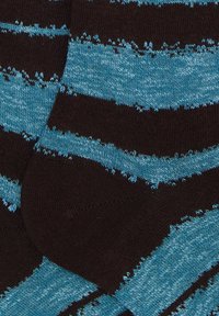 Gestreifte Socken mit abwechselnden blauen und schwarzen Farben, einer weichen Stricktextur und ausgefransten Rändern in einem lässigen Muster.