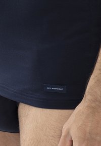 Dark navy blue men's tank top with a smooth texture, featuring a label with "MEY BODYWEAR" on the lower hem.