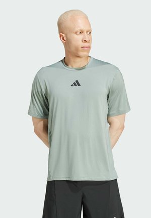 Maglietta atletica verde chiaro a manica corta realizzata in tessuto morbido, con un logo Adidas nero sul petto e un design a vestibilità rilassata.