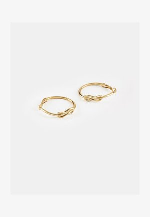 Paire de boucles d'oreilles créoles en or avec un design torsadé et de petites pierres claires incrustées sur fond blanc.