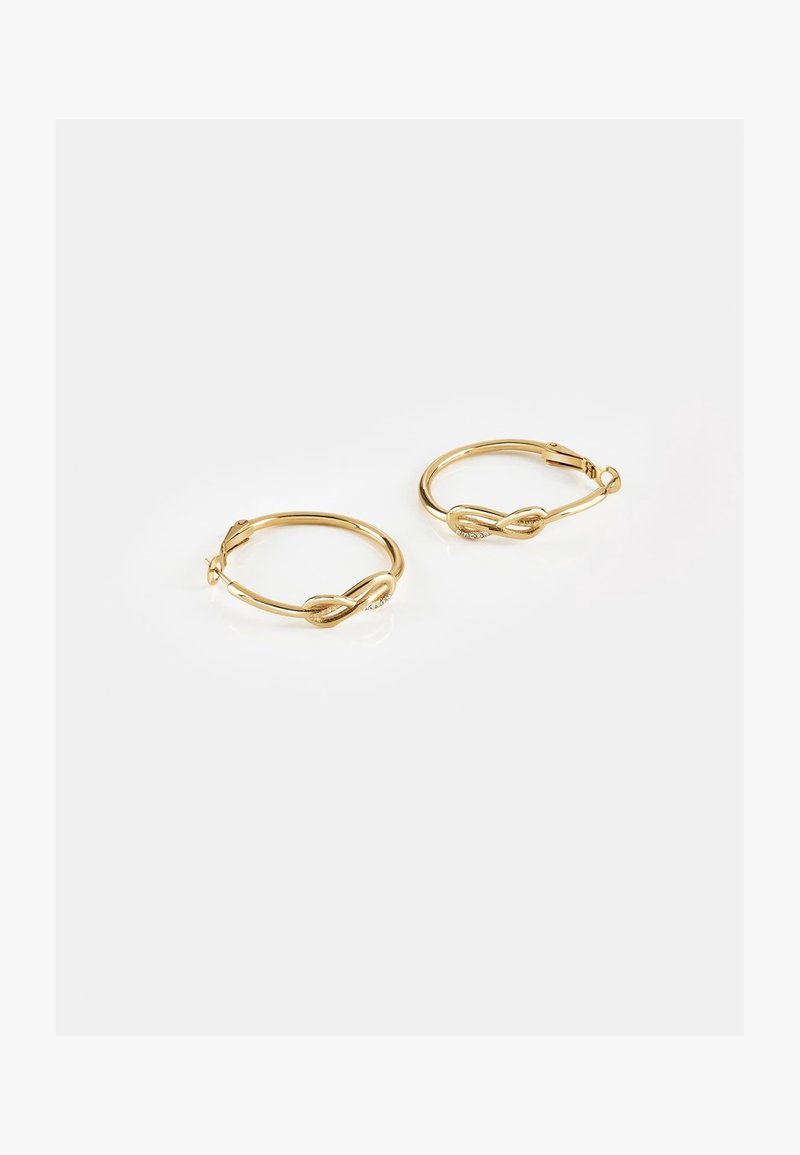 Paire de boucles d'oreilles créoles en or avec un design torsadé et de petites pierres claires incrustées sur fond blanc.