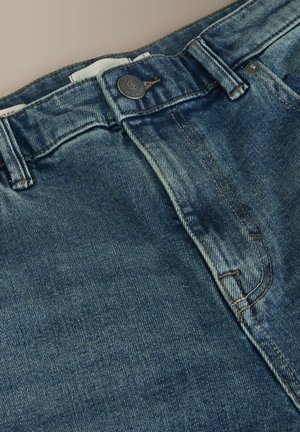 Siniset farkut, joissa haalistettu pesu, napillinen suljenta, viiden taskun malli ja tikatut yksityiskohdat saumoissa.