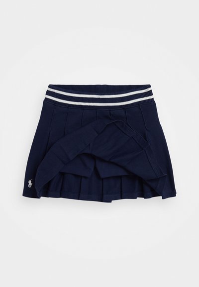 Mørkeblå plisserte skjørt med ribbestrikket midje som har hvite striper. Inkluderer en liten brodert logo på nederste kant. Stoffet er glatt og litt elastisk.