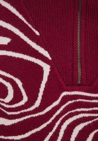 Sweter dzianinowy w głębokiej czerwieni z białym abstrakcyjnym wzorem w spiralę. Posiada prążkowany dekolt oraz półzamek z uchwytem w złotym tonie.