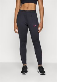 Sorte treningsleggings laget av elastisk stoff med elastisk midjebånd. Har en rosa Nike-logo på venstre lår og en tettsittende design.
