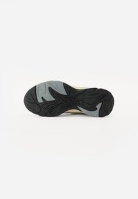 De zool van de schoen is voorzien van een getextureerde zwarte rubberen bovenkant met een golvend grijs patroon en een gelige tussenzool. Ideaal voor grip en stabiliteit.