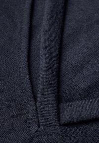 Tessuto lavorato di colore blu navy con una finitura liscia, che mostra pieghe e cuciture lungo un scollo a V. Offre una visione ravvicinata della trama del materiale.