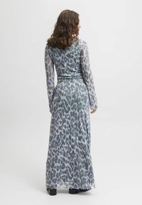Lang, gennemsigtig kjole i grå med leopardm�ønster. Har lange ærmer og en tætsiddende talje, med en svævende nederdel og bølget kant.
