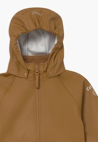 Brun vattentät jacka med hög krage och justerbar huva, med dragkedjestängning och tryckknappar, mjukt fleecefoder och logodetalj.