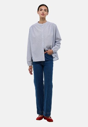 Chemise à rayures bleu clair et blanche, coupe décontractée. Assortie à un jean bleu taille haute et des ballerines rouges. Manches longues, col rond.