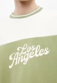 Groen en crème katoenen T-shirt met vintage-stijl "Los Angeles" print in wit, ronde hals met contrasterende geribbelde boord.