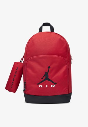 Czerwono-czarny plecak z przednią kieszenią, czarnym logo "Air Jordan" oraz przymocowaną cylindryczną czerwoną saszetką z napisem "Jordan" w kolorze czarnym.