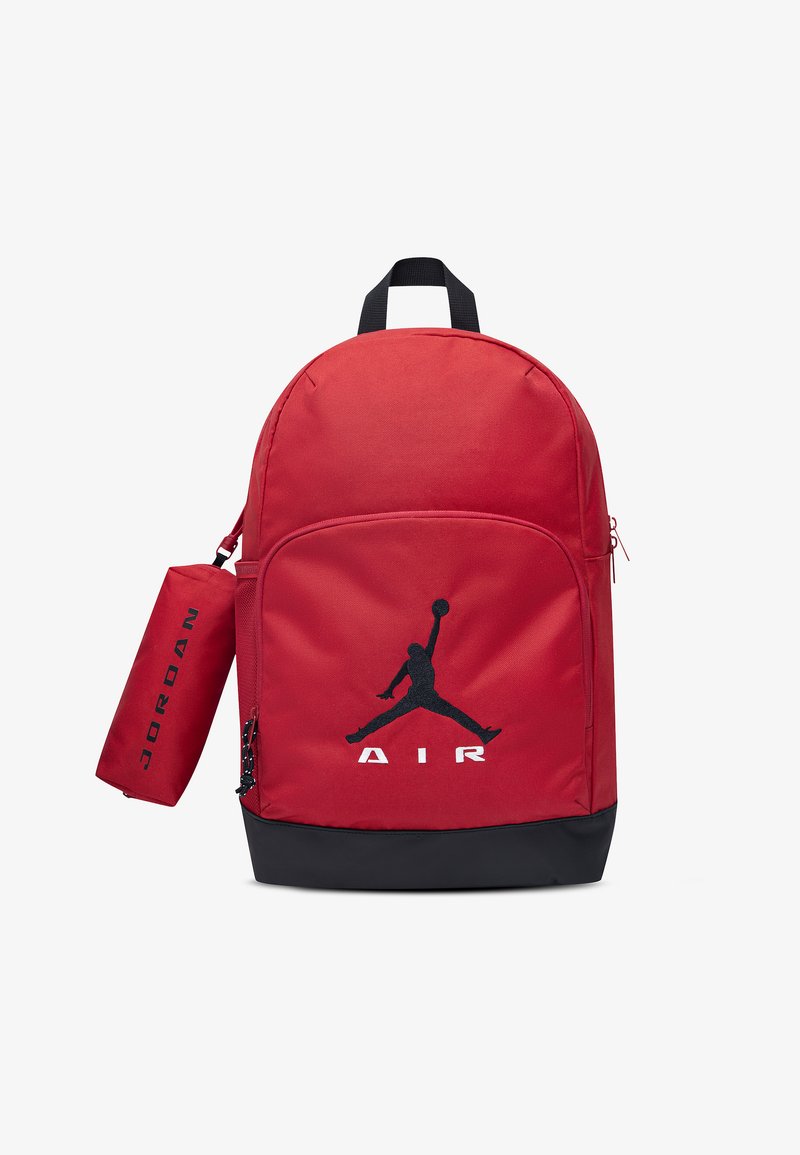 Κόκκινο και μαύρο σακίδιο πλάτης με μπροστινή τσέπη, μαύρο λογότυπο "Air Jordan" και προσαρτημένη κυλινδρική κόκκινη θήκη με το κείμενο "Jordan" σε μαύρο χρώμα.
