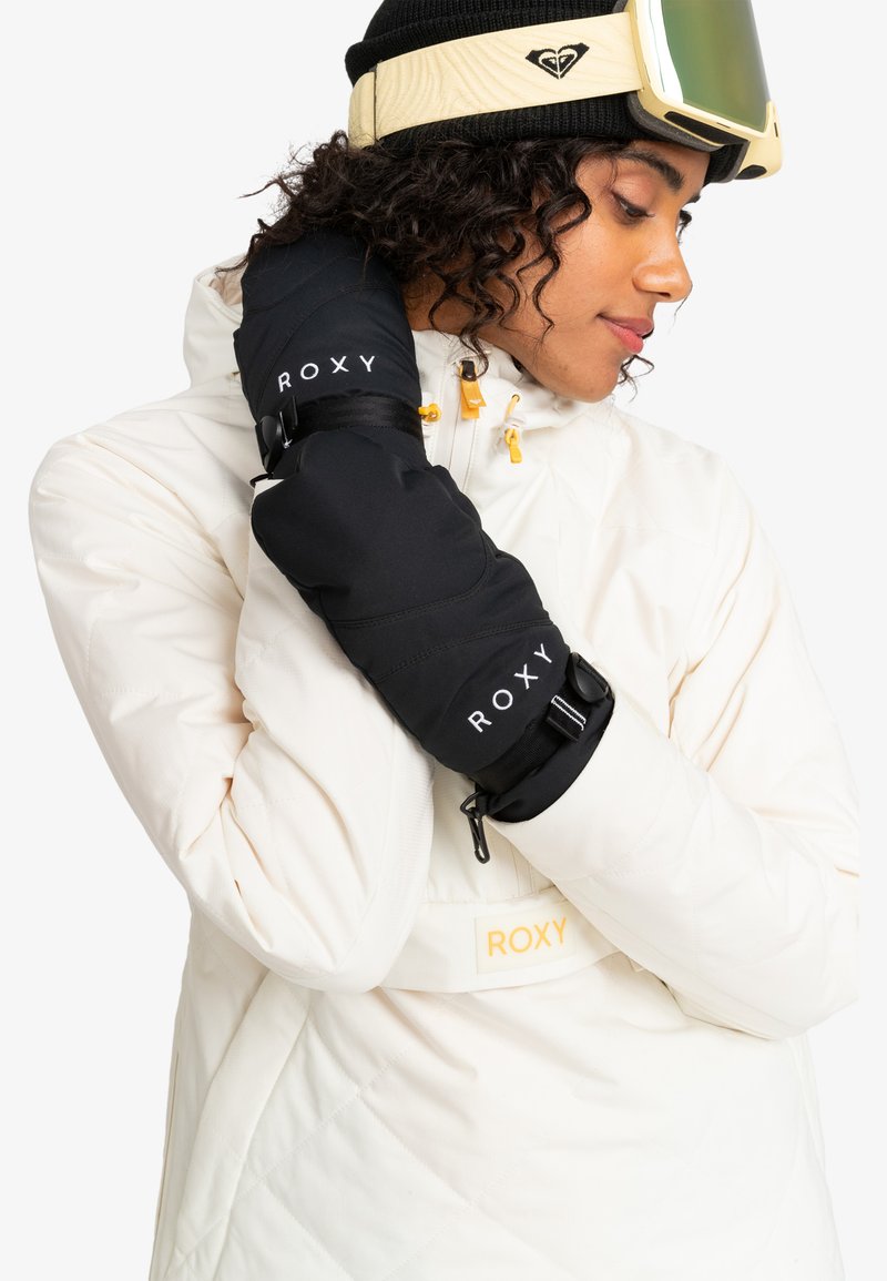 Schwarze Handschuhe mit "ROXY"-Logo, gepolstertes Design, verstellbare Riemen, getragen von einer Person in einer weißen Steppjacke mit gelben Akzenten.