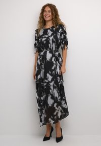 Zwart-witte tie-dye maxi jurk met korte pofmouwen,Gathered taille en verticale plooien. Gepaarde met zwarte hoge hakken.