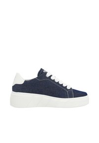 Blue denim sneaker with a white rubber sole, round toe, and six white eyelets for laces. Features a thick textured sole and contrasting stitching.