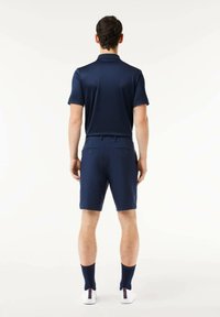 Polo de navy de manga corta combinado con pantalones cortos de navy a juego. Presenta una textura suave y un ajuste clásico. Zapatillas blancas y calcetines azules.