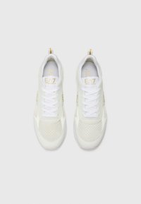 White athletic sneakers with mesh and leather design, featuring a textured upper, white laces, and gold accents on the sides and branding.