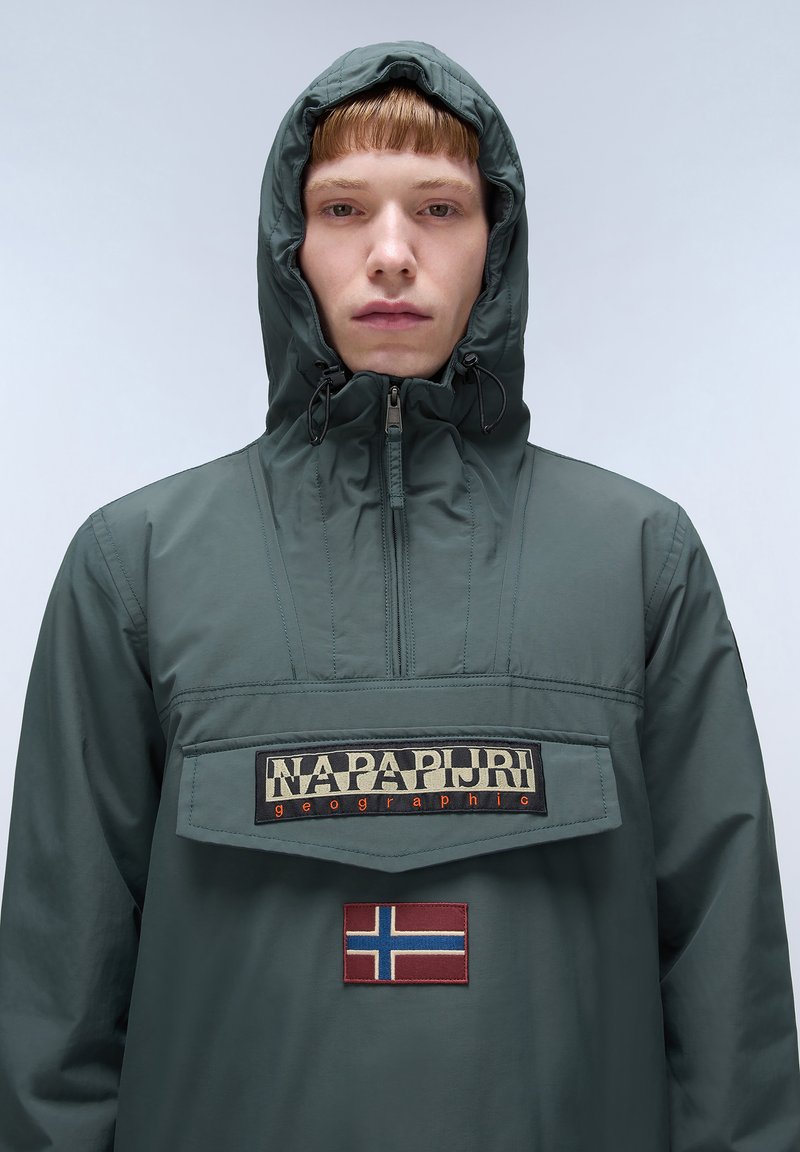 Giacca pullover verde con cappuccio, dotata di zip frontale, grande tasca a toppa e bandiera norvegese ricamata. Il materiale sembra leggero e liscio.