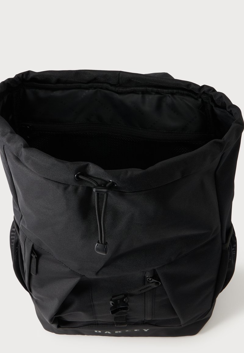 Schwarzer Oakley Rucksack mit Kordelzugverschluss, vorderer Reißverschlusstasche, seitlichen Netzfächern und offenem Hauptfach.