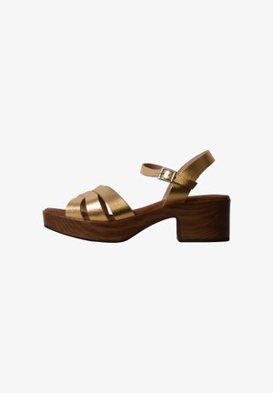 Sandale en cuir doré avec talon bloc en bois, trois brides croisées sur les orteils, bride de cheville avec fermeture à boucle.