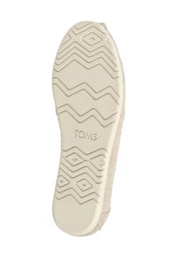 Σόλα μπεζ παπουτσιού TOMS με ανάγλυφο γεωμετρικό μοτίβο πέλματος και το λογότυπο "TOMS" εγχάρακτο στο κέντρο.