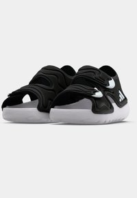 Μαύρα παπούτσια χωρίς κορδόνια με ανάγλυφη επιφ άνεια, που διαθέτουν δύο φαρδιές λουριά και παχύ, λευκό ελαστικό πάτο. Ο σχεδιασμός με ανοίγματα βελτιώνει την αναπνοή.