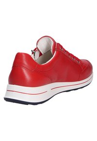 Baskets en cuir rouge, forme arrondie, semelle intermédiaire blanche avec une stripe rouge, col rembourré, trois œillets avec quincaillerie en argent, texture lisse.