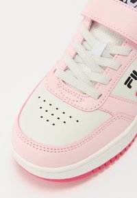 Baskets blanches et roses avec une finition en cuir lisse, dotées d'un bout perforé, de lacets gris clair et d'une semelle en caoutchouc rose.